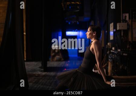 Danseuse de ballet adulte penchée en arrière tout en étant assise derrière la scène avant le spectacle Banque D'Images