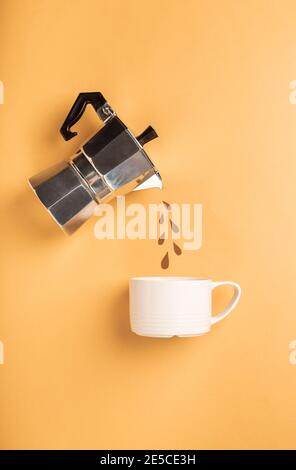 Des gouttes de papier déversées à partir d'une cafetière geyser dans une tasse sur fond de papier marron clair. Concept de préparation du café. Vue de dessus, plan d'appartement. Minimale Banque D'Images
