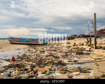 Kaimana, Arguni Bay, Indonésie - février 2018 : problème de pollution. Bateaux en bois et plein de déchets sur la plage à marée basse au port d'un petit Banque D'Images