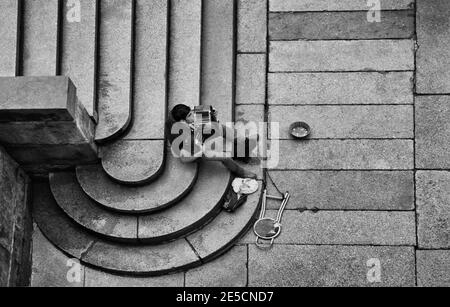 Vue d'en haut sur un musicien de rue assis sur le escaliers Banque D'Images