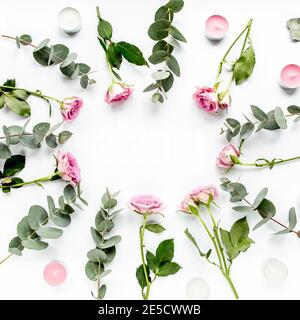 cadre en forme de couronne avec roses, branches d'eucalyptus, feuilles isolées sur fond blanc. flat lay, vue de dessus Banque D'Images