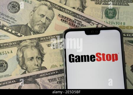 Logo de la société de vente au détail Gamestop sur le smartphone placé sur des dollars américains. Stafford, Royaume-Uni - janvier 27 2021. Banque D'Images