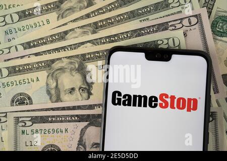 Logo de la société de vente au détail Gamestop sur le smartphone placé sur des dollars américains. Stafford, Royaume-Uni - janvier 27 2021. Banque D'Images