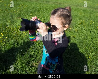 Fille debout à l'extérieur prenant une photo avec un appareil photo reflex numérique, Italie Banque D'Images