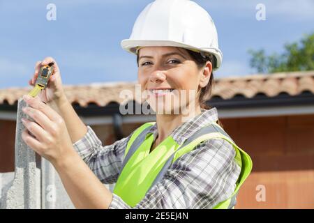 belle femme dans un casque mesurant un mur Banque D'Images