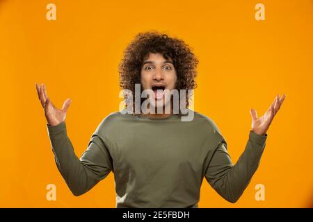 UN JEUNE HOMME AUX CHEVEUX BOUCLÉS HURLE DEVANT PAR SURPRISE DE LA CAMÉRA Banque D'Images