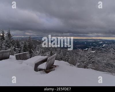 Bancs de repos en bois et tables couverts de neige profonde avec vue panoramique sur les montagnes de la Forêt-Noire avec des conifères enneigés. Banque D'Images