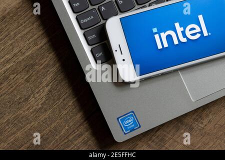 Le nouveau logo Intel apparaît en arrière-plan sur un smartphone avec un PC portable étiqueté Intel Inside le 25 janvier 2021. Banque D'Images
