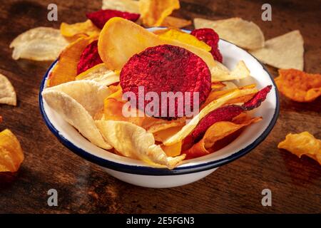 Chips de légumes, en-cas bio sain, dans un bol sur fond de bois rustique foncé Banque D'Images