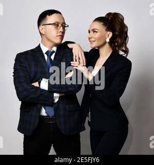 Portrait de l'homme et de la femme partenaires d'affaires collègues dans les costumes officiels debout près, elle est penchée sur son épaule Banque D'Images