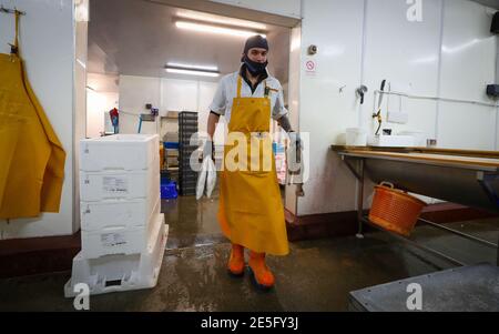 Un membre du personnel de Midland Fish à Fleetwood transporte du poisson préparé pour la vente aux quais de Fleetwood, dans le Lancashire. L'introduction de nouveaux contrôles et de nouvelles formalités depuis la fin de la période de transition du Brexit le 31 décembre a causé d'énormes perturbations aux exportations de poisson et de fruits de mer frais vers l'UE, les producteurs devenant de plus en plus frustrés par l'absence d'action gouvernementale. Date de la photo: Jeudi 28 janvier 2021. Banque D'Images