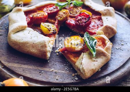 Galette savoureuse aux tomates fraîches colorées et au basilic sur une table en bois. Concept végétarien de nourriture saine. Banque D'Images