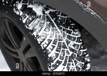 Roue de voiture de vus sale. Pneu à neige avec crampons métalliques, qui améliorent la traction sur les surfaces glacées, photo en gros plan avec mise au point sélective Banque D'Images