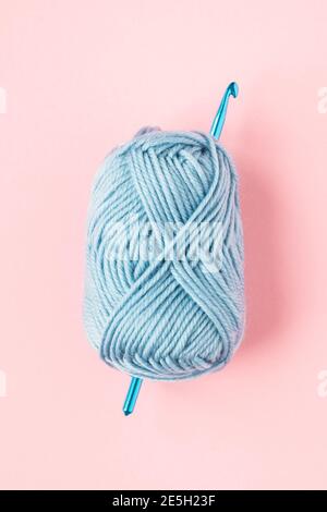 Crochets en crochet avec boule bleue de fil sur un rose arrière-plan Banque D'Images