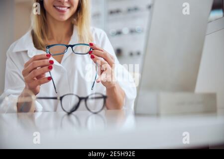 Élégante femme charmante en chemisiers blancs choix de nouveaux objectifs pour lunettes en clinique d'ophtalmologie Banque D'Images