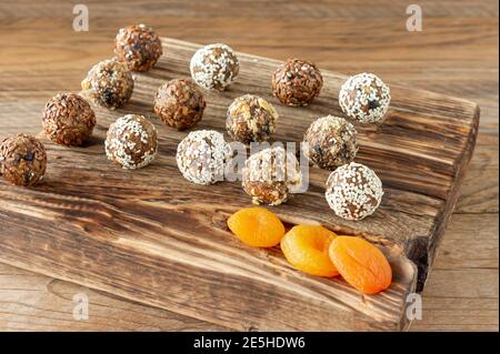 Boules d'énergie faites maison avec abricots séchés, raisins secs, dattes, pruneaux, noix de Grenoble, amandes et noix de coco sur fond de bois. Des aliments sains et sucrés Banque D'Images