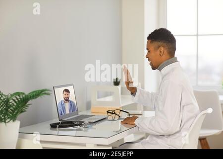 Jeune homme noir souriant médecin thérapeute faisant la consultation en ligne Banque D'Images
