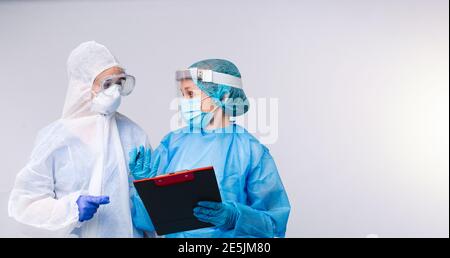 Bannière,format long. Deux médecins en équipement médical et une liste de patients qui ont été testés positifs pour le covid 19. Arrière-plan blanc espace latéral vide. Banque D'Images