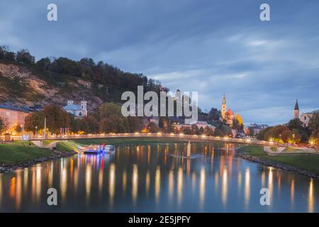 Vue nocturne sur la rivière Salzach à Salzbourg, le pont piétonnier de Marko-Feingold-Steg en Autriche et l'église Pfarre Mulln Banque D'Images