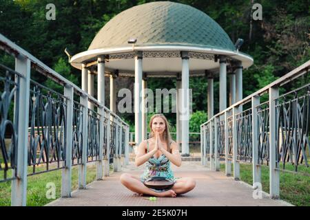 Belle hipster femme assise dans le parc et jouant dessus joyeux tambour et chant Banque D'Images