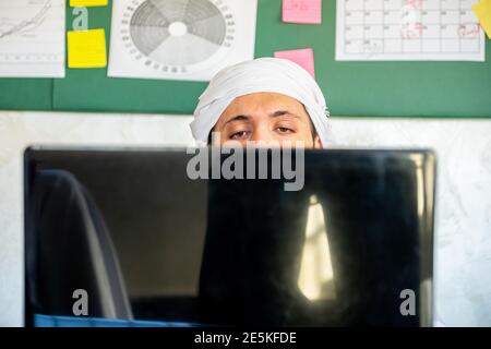 Le jeune arabe pense dans son travail avec un regard sérieux sur son visage devant cet ordinateur portable Banque D'Images