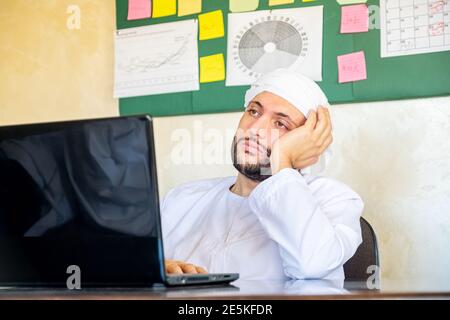 le jeune homme arabe est élevé dans son travail devant lui de cet ordinateur portable Banque D'Images