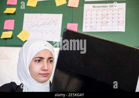 Femmes musulmanes travaillant au bureau depuis leur domicile à l'aide d'un ordinateur portable Banque D'Images