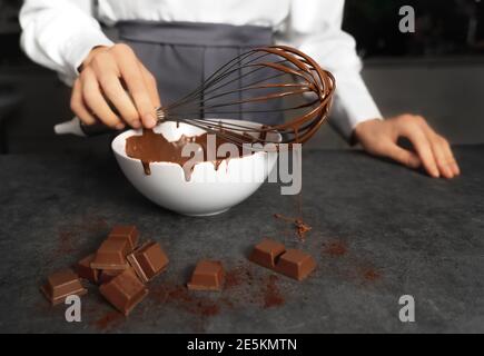 Jeune femme qui fabrique des truffes au chocolat. Arrière-plan sombre. Concept de cuisine délicieuse. Un design parfait pour toutes les applications. Banque D'Images