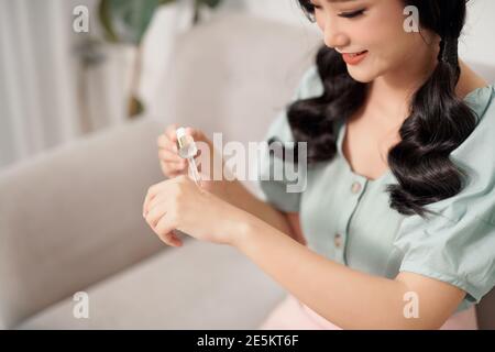 Belle jeune femme utilise le traitement hydratant anti-âge sérum sur Ses mains Banque D'Images