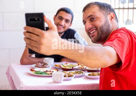 L'homme musulman et son ami prennent le selfie et mangent petit déjeuner Banque D'Images