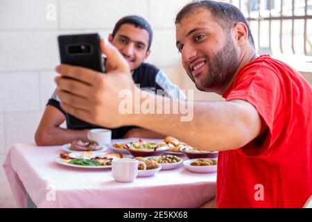 L'homme musulman et son ami prennent le selfie et mangent petit déjeuner Banque D'Images