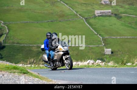 Motocycliste avec pilot sur le col des Butterbeans entre Muker et Hawes dans le parc national de Yorkshire Dales, Royaume-Uni. Banque D'Images