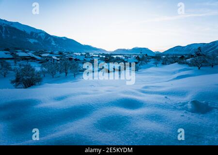 Paysage alpin d'hiver recouvert de neige au crépuscule bleu avec vue sur le petit village traditionnel autrichien de Wildermieming, Tirol, Autriche Banque D'Images