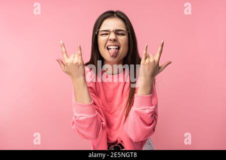 Photo d'une femme attirante en lunettes, mouvement rock-and-roll et amusant, porte décontracté t-shirt rose pantalon blanc isolé couleur rose fond Banque D'Images