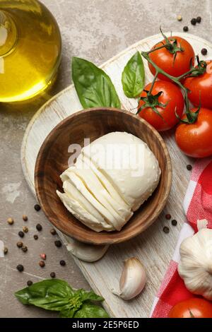 Concept de repas savoureux avec mozzarella et ingrédients à bord sur table texturée grise Banque D'Images