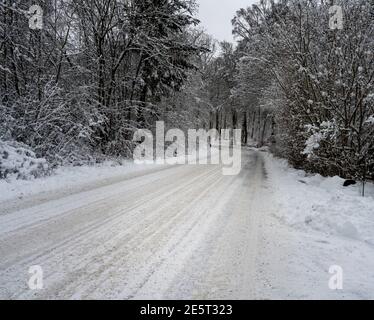 Une route d'hiver verglacée et enneigée traversant une forêt. Photo de Scania, sud de la Suède Banque D'Images