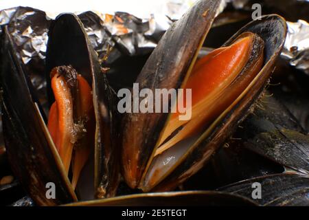 Livraison de nourriture dans un emballage en plastique à votre maison. Moules dans une sauce en papier d'aluminium et contenant en plastique sur fond jaune. Banque D'Images