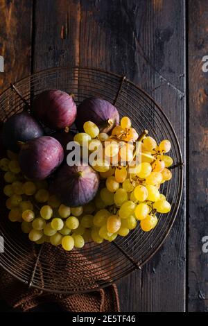 Concept rétro vintage. Raisins frais et figues sur un arrière-plan en bois ancien de style rétro. Vue de dessus. Banque D'Images