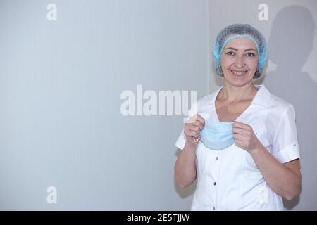 Vaccination contre le coronavirus. L'infirmière sourit, tenant un masque médical, sur un fond clair, copier l'espace à gauche. Préparation de la procédure Banque D'Images