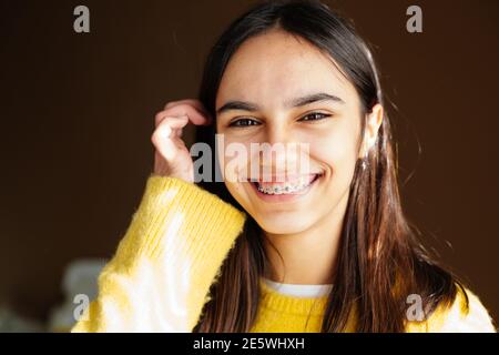 Portrait d'une jeune fille heureuse avec des bretelles et certains acné souriant à la maison avec le soleil venant par le fenêtre Banque D'Images