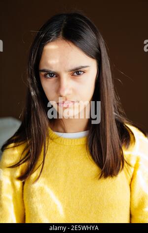 Portrait d'une jeune fille malheureuse et mécontente avec un chandail jaune à la maison regardant l'appareil photo Banque D'Images