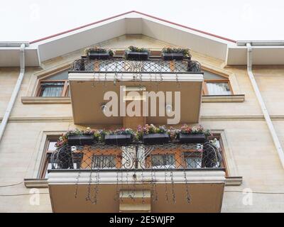 Maison à la riche décoration en marbre et balcons avec décoration noire treillis forgé et fleurs sur eux Banque D'Images