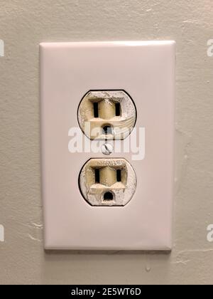 Prise murale électrique blanche avec deux prises montées sur un mur peint en vert. Banque D'Images