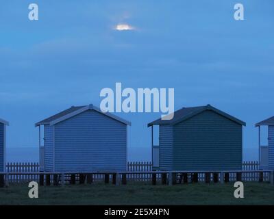 Leysdown, Kent, Royaume-Uni. 28 janvier 2021. Météo au Royaume-Uni : la pleine lune du loup s'élève au-dessus des cabanes de plage à Leydown, dans le Kent - la première pleine lune de 2021. Crédit : James Bell/Alay Live News Banque D'Images