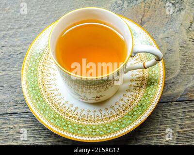 Thé chaud dans une image vintage d'une ancienne tasse de thé chaud victorienne dans la soucoupe sur fond de bois Banque D'Images