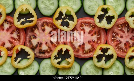 Tomate, concombres et poivre. Tranches de légumes sur fond noir. Photo de haute qualité Banque D'Images