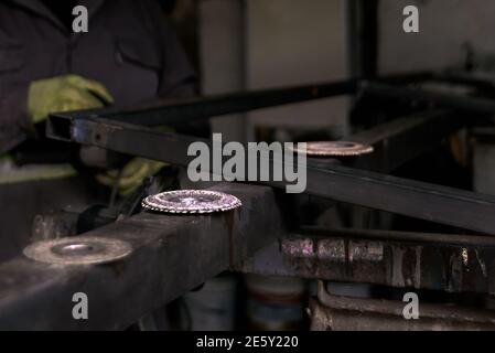 Photo d'un homme méconnaissable portant des gants spéciaux travaillant dans un atelier de forgeron. Banque D'Images