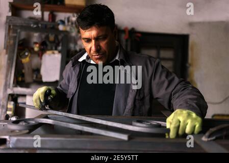 Photo de l'homme concentré travaillant dans un atelier de forgeron. Banque D'Images