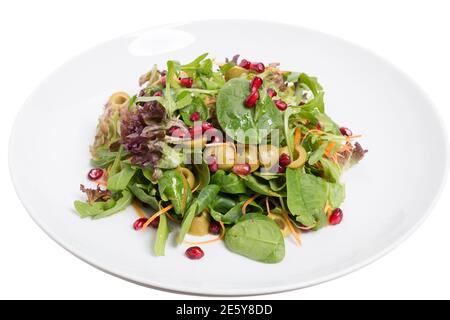 Salade d'épinards et de grenade dans la plaque blanche. Il est situé sur un fond blanc. Gros plan. Banque D'Images