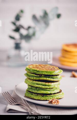 Crêpes vertes avec thé au matcha ou aux épinards, miel et raisins rouges. Petit déjeuner sain avec des superaliments. Arrière-plan clair, style scandinave élégant Banque D'Images